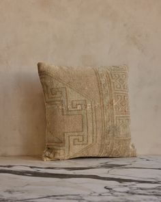 a pillow sitting on top of a marble counter next to a wall with a brown and white pattern