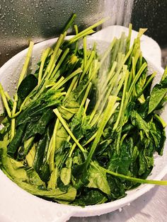 a white bowl filled with green vegetables on top of a table