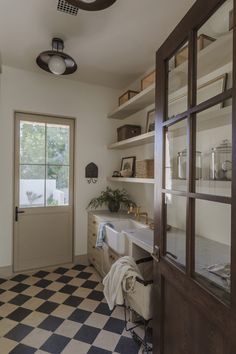 a kitchen with black and white checkered flooring next to a doorway that leads to a patio