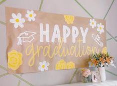 a sign that says happy graduation with flowers in front of it and a vase full of flowers next to it