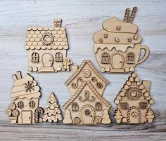 wooden cutouts of christmas houses and trees on a table with white wood planks