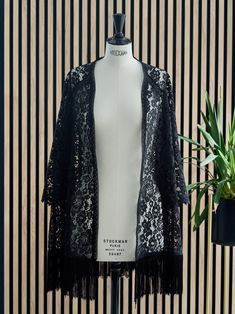 Three-quarter length black lace kimono with long, wide sleeves that ends in beautiful lace details. The length of the sleeve is also three quarters, it has crochet straps on the front and back and borders the entire neckline. On the bottom it has black fringes that make a nice movement when walking. Ideal for any type of look, it is a very versatile garment that can be combined with jeans or a dress for a more formal event. Long Sleeve Fringe Kimono For Festivals, Festival Long Sleeve Kimono With Fringe, Long Sleeve Festival Kimono With Fringe, Spring Long Sleeve Fringed Kimono, Spring Fringe Long Sleeve Kimono, Fringe Kimono For Beach In Fall, Spring Fringed Long Sleeve Kimono, Long Sleeve Fringe Cover-up For Spring, Spring Long Sleeve Fringe Cover-up