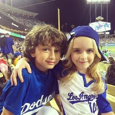 two young baseball players are posing for a photo at a game in front of the crowd