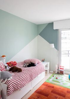 two cats laying on top of a bed in a room with blue and green walls