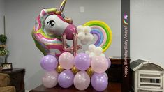 an inflatable unicorn balloon is on top of a table next to other balloons