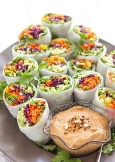 a platter filled with rolls covered in veggies and topped with peanut butter