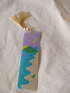 a beaded bookmark with a tassel hanging from it's side on a white surface