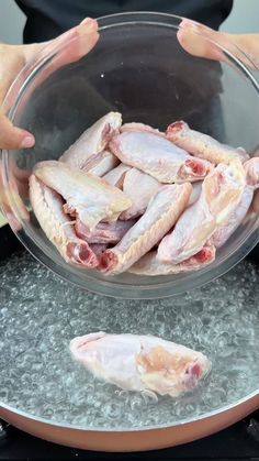 a person holding a glass bowl filled with raw chicken