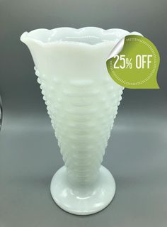 a white vase sitting on top of a table next to a glass container with a price tag