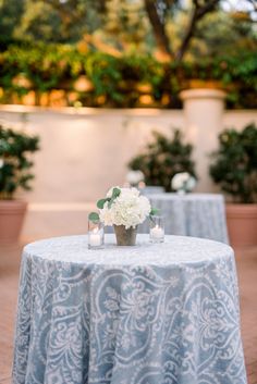 the table is set with white flowers and candles in vases on top of it