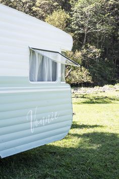 a white trailer parked on top of a lush green field