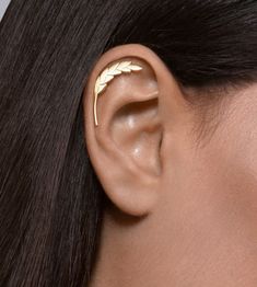 a woman's ear with two gold leaves on it