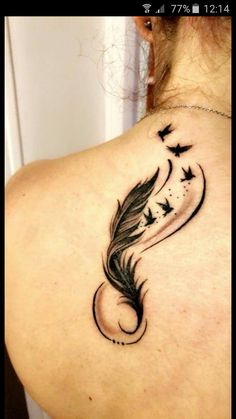 the back of a woman's neck with a feather and stars tattoo on it