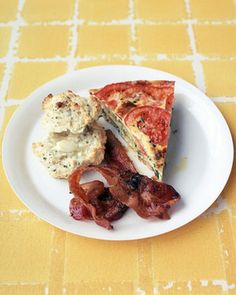 a white plate topped with slices of pizza next to bacon on a yellow tablecloth