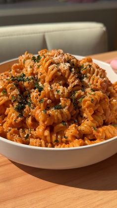 a white bowl filled with pasta on top of a wooden table