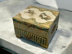 an elaborately decorated box sitting on top of a stone slab in front of a white wall