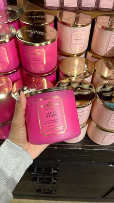 a person is holding up a pink candle in front of many other candles that are stacked on top of each other