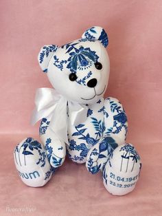 a blue and white teddy bear sitting on top of a pink surface