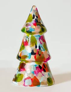 a colorful glass christmas tree sitting on top of a white table next to a wall