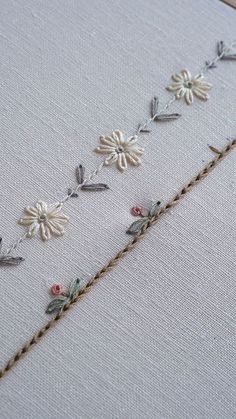 the embroidery is being worked on by someone using scissors and thread to make it look like flowers