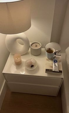 a table with a lamp, bowl and cup on it next to a candle holder