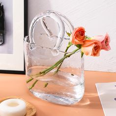 a vase filled with water and flowers on top of a table next to a candle