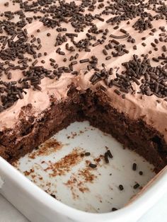 a cake with chocolate frosting and sprinkles in a white baking dish