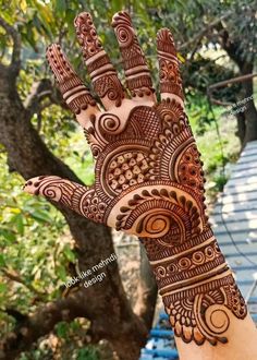 a hand with henna on it and some trees in the backgroung