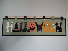 a sign that says halloween hanging from the side of a wall with cats and pumpkins on it