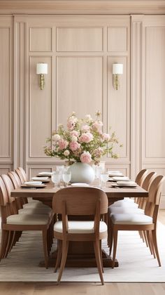 a dining room table with chairs and flowers in a vase on the top of it