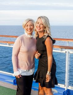 two women standing next to each other in front of the ocean on a cruise ship