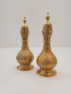 two golden vases sitting side by side on a white surface with no one around them