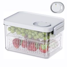 a plastic container filled with green and red fruits next to a white button on the side