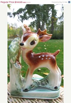 a ceramic deer figurine sitting on top of a table next to a tree