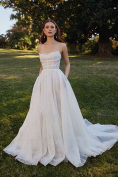 a woman in a white wedding dress standing on the grass