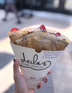 a person holding up a cupcake with strawberries in it's wrapper