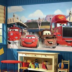 a room with cars painted on the wall and children's furniture in front of it