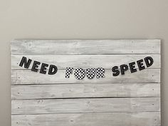 a wooden sign that says need to speed with checkered flags hanging from it's sides