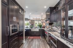 a kitchen with dark wood cabinets and marble counter tops, along with stainless steel appliances