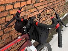 a bicycle parked against a brick wall with its handlebars and saddle bag attached to it