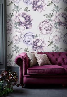 a purple couch sitting in front of a wall with flowers painted on the wall behind it