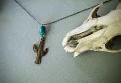 Sanguaro- Vintage Brass Cactus and Real Southwest Turquoise Necklace A vintage brass sanguaro cactus dangles from a real piece of turquoise and hangs from an oxidized sterling silver chain. The cactus pendant has a gorgeous natural patina and a wonderful texture. I love the color of the traditional dog bone shaped southwest turquoise that sits atop the cactus. The whole pendant measures 1 1/2 inches high. It is hung on your choice of a brass chain, a shiny sterling silver chain or an oxidized st Bohemian Sterling Silver Turquoise Necklace With Patina, Bohemian Sterling Silver Necklace With Patina, Turquoise Bohemian Brass Jewelry, Bohemian Hand Forged Sterling Silver Turquoise Necklace, Bohemian Turquoise Brass Jewelry, Southwestern Hand Forged Turquoise Jewelry, Southwestern Style Hand Forged Turquoise Jewelry, Turquoise Bohemian Jewelry With Vintage Charm, Bohemian Turquoise Jewelry With Vintage Charm