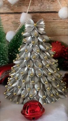 a christmas tree made out of silver tinsels and red ornaments on a table