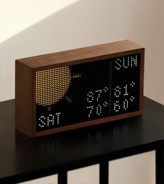 an electronic clock with the time displayed on it's display board, sitting on a table