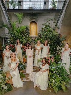 a group of bridesmaids posing for a photo in front of some greenery