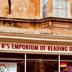 a store front with signs on the windows and an old building in the background that says, b's emporum of reading books