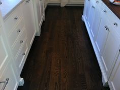 a kitchen with white cabinets and wood floors