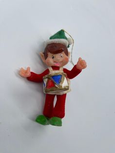 an elf ornament hanging on the wall with his hands in the air and one hand out