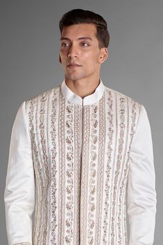 White sherwani with scallop, floral and paisley embroidery in a stripe pattern. Comes with straight fit cotton silk kurta and trouser.
Components: 3
Pattern: Embroidery
Neckline: Band Collar
Sleeve Type: Long
Fabric: Silk Linen
Color: White
Other Details: 
Slits on the sides
Note: The flared inner kurta and shawl worn by the model is not for sale
Occasion: Wedding - Aza Fashions Fitted Traditional Wear With Embroidered Border For Formal Occasions, Fitted Sherwani With Embroidered Border In Traditional Drape, Fitted Sherwani With Embroidered Border For Transitional Season, Elegant Sherwani With Embroidered Border, Elegant Formal Sherwani With Embroidered Border, Elegant Fitted Sherwani With Embroidered Border, Fitted Bandhgala With Embroidered Border For Festivals, Fitted Bandhgala With Embroidered Border For Festive Occasions, Elegant Long Sleeve Sherwani With Embroidered Border