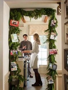 a man and woman standing next to each other in front of a doorway covered with greenery